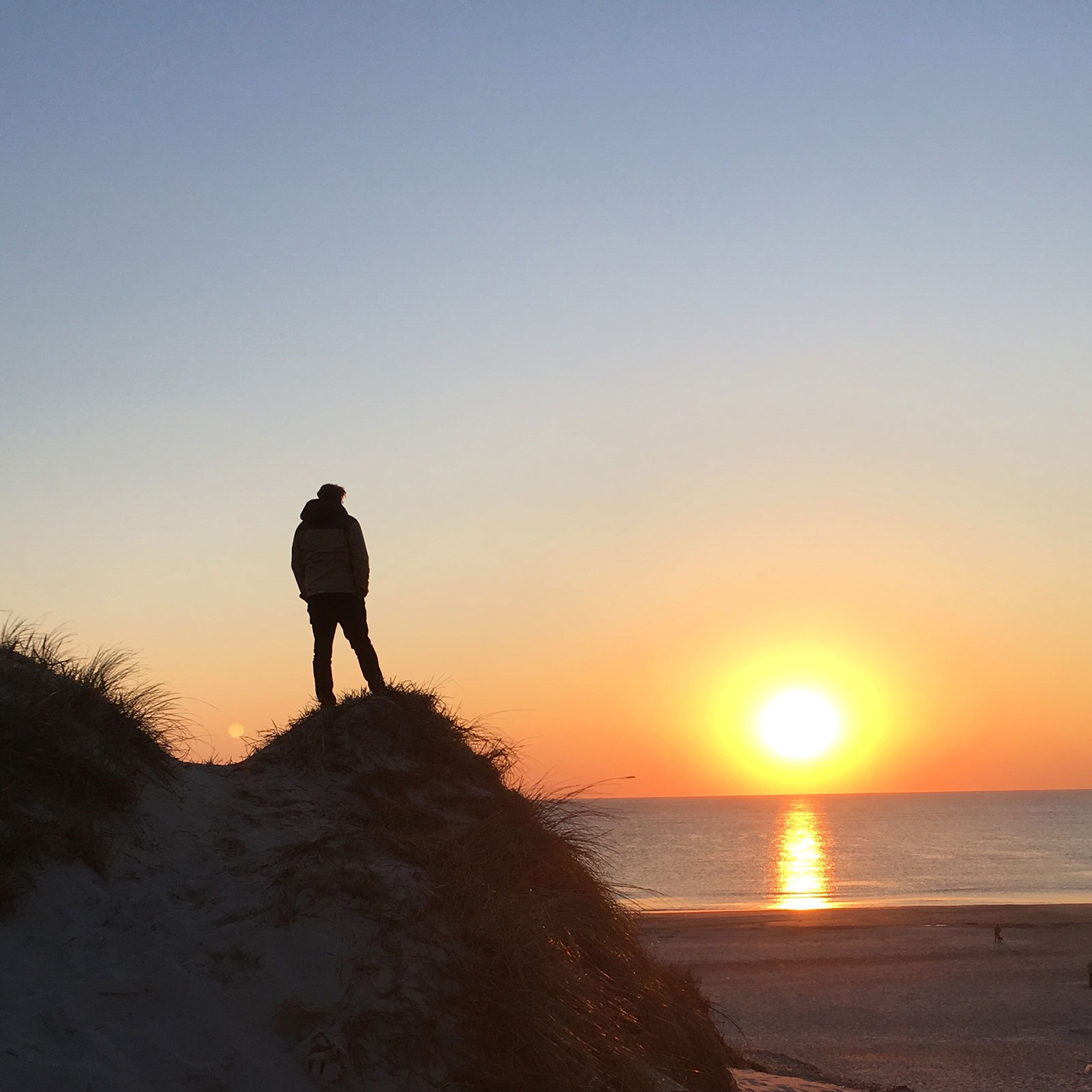Blick von den Dünen auf den Sonenuntergang am Horizont